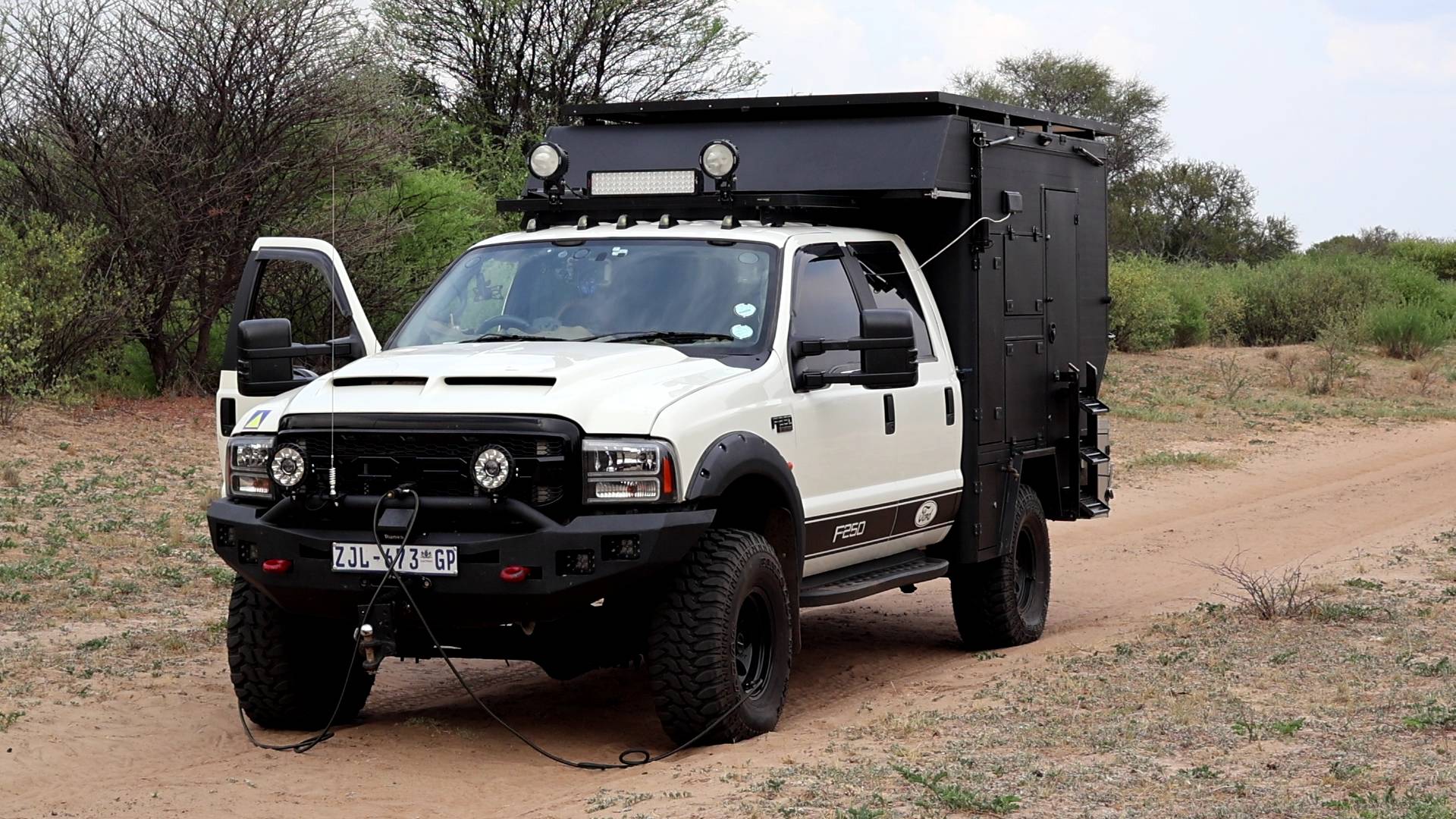 White Ford F250 overlanding truck on a Kalahari sand track at sunset